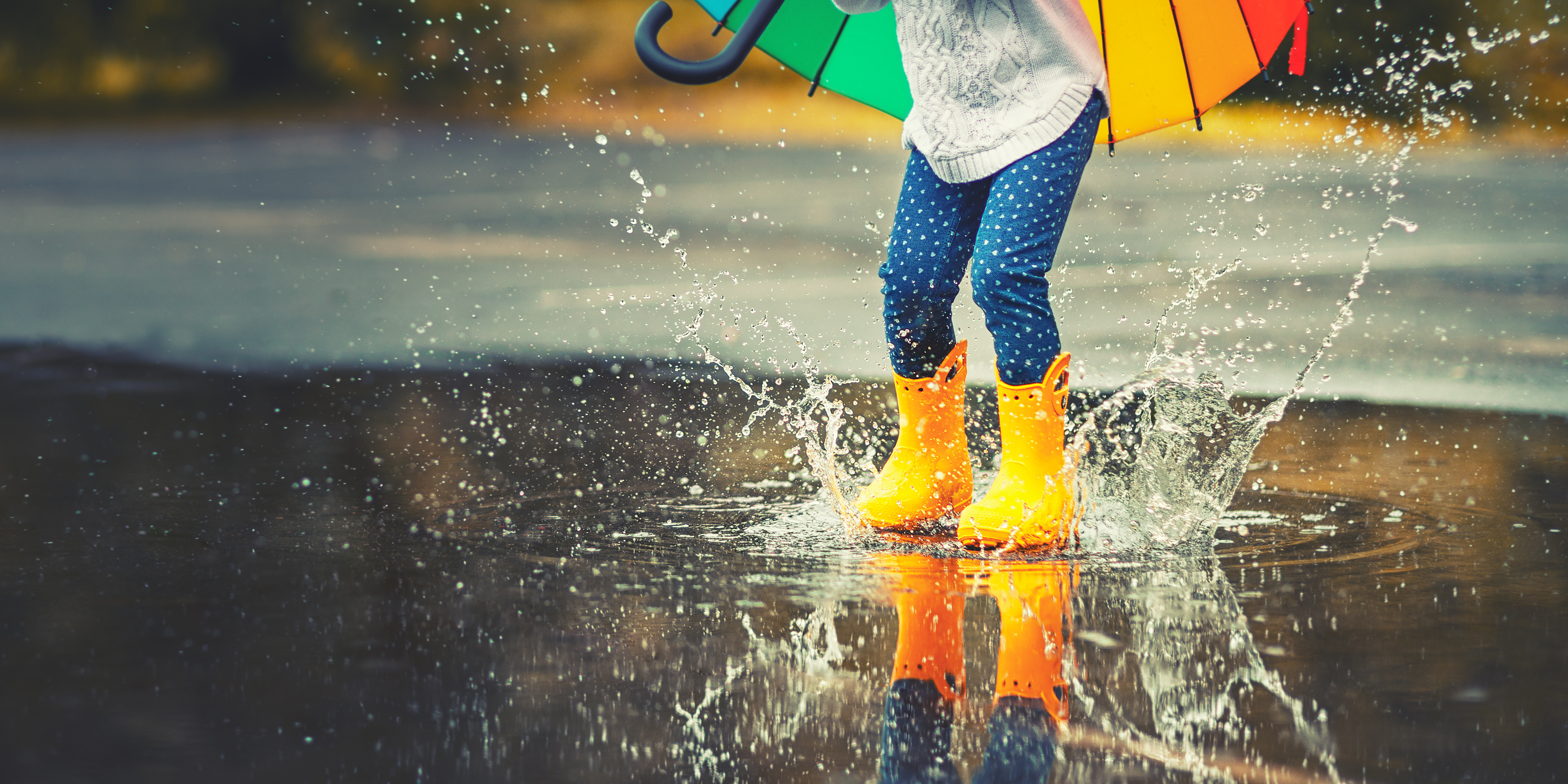 Enfant sautant dans une flaque avec un parapluie coloré